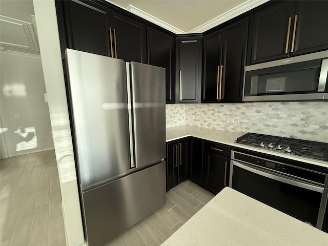 10307 Harmon Smith Dr, Houston, TX 77025 - kitchen featuring stainless steel appliances, dark cabinetry, wood tiled floors, tasteful backsplash, and ornamental molding