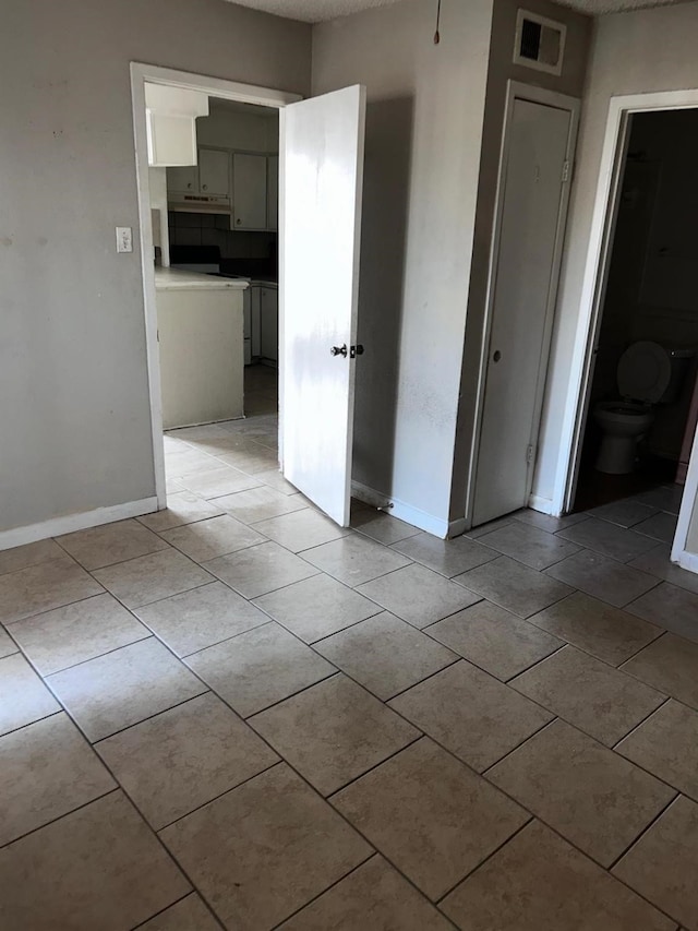 12615 Brookglade Cir Unit 407, Houston, TX 77099 - unfurnished bedroom featuring baseboards, light tile patterned floors, and a textured ceiling