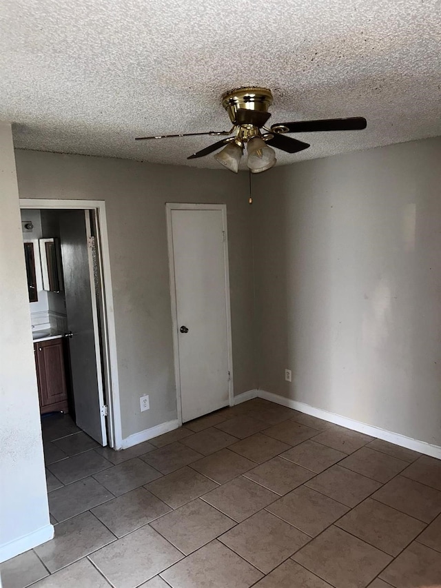 12615 Brookglade Cir Unit 407, Houston, TX 77099 - spare room featuring tile patterned flooring, a ceiling fan, a textured ceiling, and baseboards
