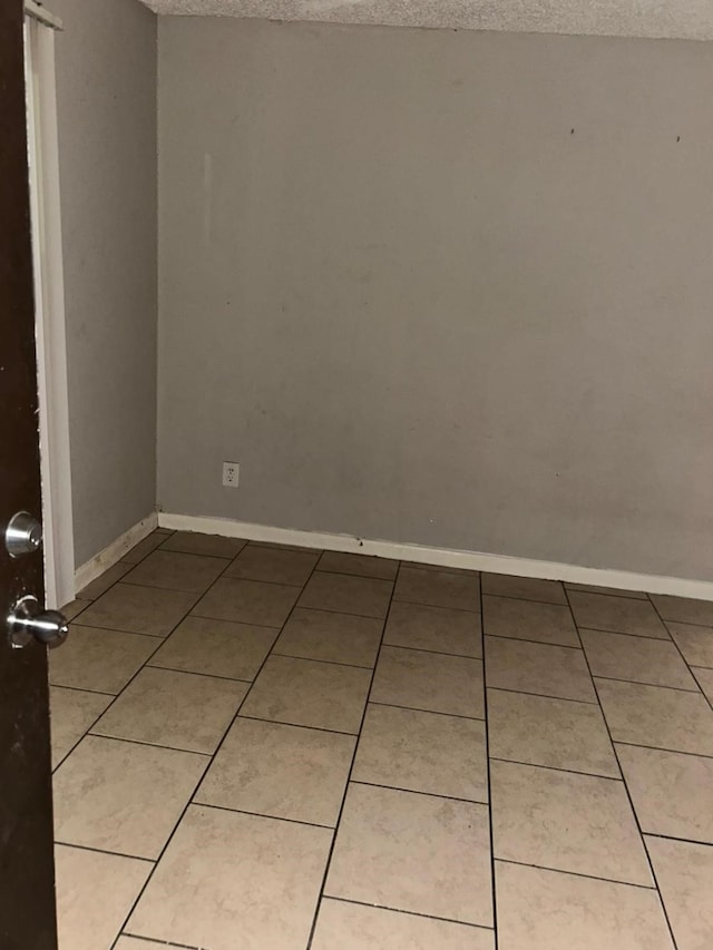 12615 Brookglade Cir Unit 407, Houston, TX 77099 - empty room featuring a textured ceiling, light tile patterned flooring, and baseboards