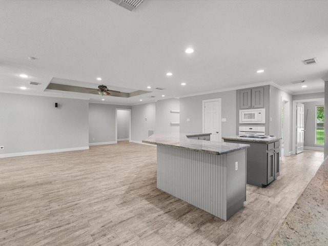 5401 Palm Dr, Dickinson, TX 77539 - kitchen featuring a center island, white microwave, gray cabinetry, baseboards, and crown molding
