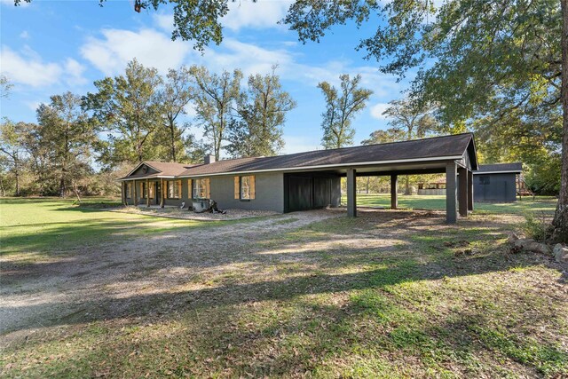 14232 Calhoun Rd, Conroe, TX 77302 - rear view of house featuring a carport, a lawn, a chimney, and driveway