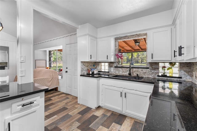 14232 Calhoun Rd, Conroe, TX 77302 - kitchen with a sink, decorative backsplash, wood finished floors, white cabinets, and dark stone counters