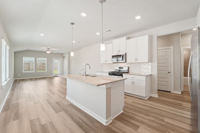 18733 Bliss Pl, New Caney, TX 77357 - kitchen with stainless steel appliances, a sink, tasteful backsplash, light wood-style flooring, and white cabinetry