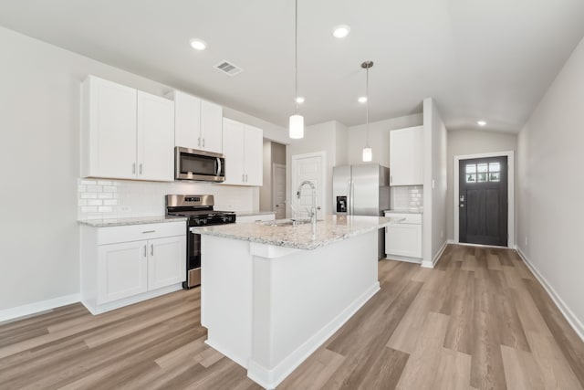 18733 Bliss Pl, New Caney, TX 77357 - kitchen featuring stainless steel appliances, a sink, decorative backsplash, white cabinetry, and light wood-style floors