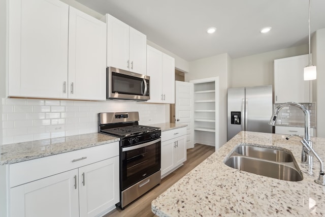 18733 Bliss Pl, New Caney, TX 77357 - kitchen featuring stainless steel appliances, a sink, light wood-style floors, white cabinets, and recessed lighting