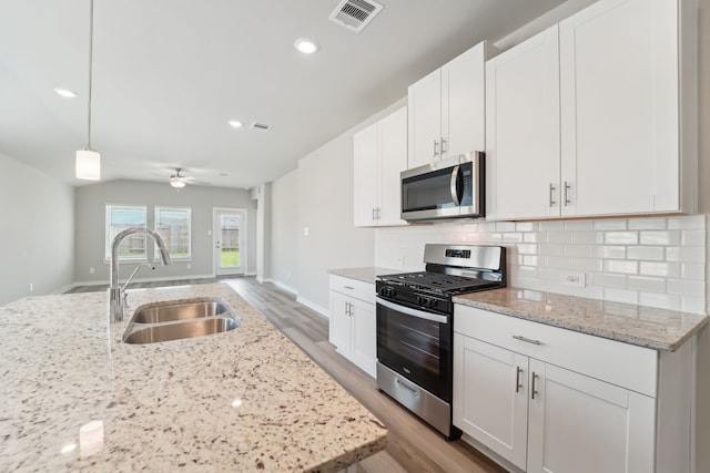 18733 Bliss Pl, New Caney, TX 77357 - kitchen featuring appliances with stainless steel finishes, a sink, light wood-style flooring, tasteful backsplash, and ceiling fan