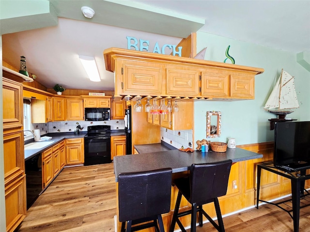 16611 Jolly Roger Rd, Jamaica Beach, TX 77554 - kitchen with black appliances, tasteful backsplash, a sink, and light wood-type flooring