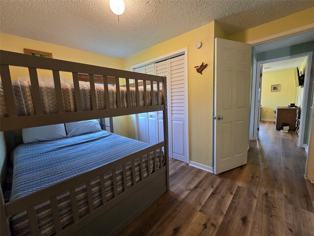 16611 Jolly Roger Rd, Jamaica Beach, TX 77554 - bedroom with wood finished floors, a textured ceiling, baseboards, and a closet