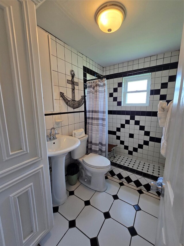 16611 Jolly Roger Rd, Jamaica Beach, TX 77554 - bathroom with tiled shower, tile walls, tile patterned floors, and toilet