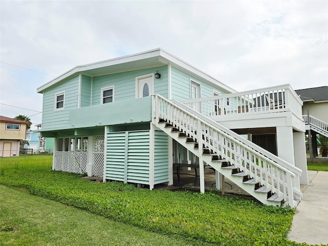 16611 Jolly Roger Rd, Jamaica Beach, TX 77554 - rear view of house featuring stairway, a lawn, and a wooden deck