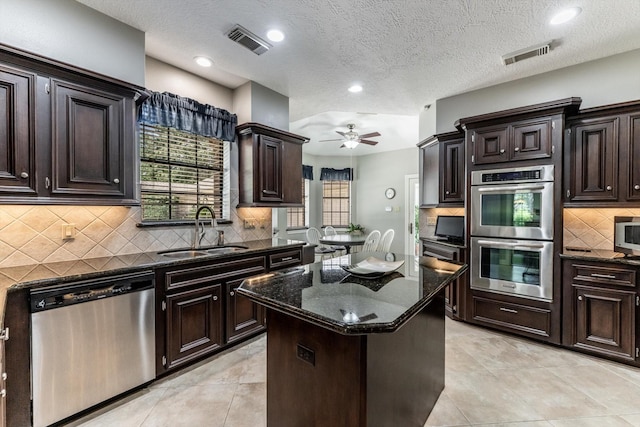 17718 Dove Tree Ln, Spring, TX 77379 - kitchen featuring appliances with stainless steel finishes, a sink, dark stone countertops, a kitchen island, and ceiling fan