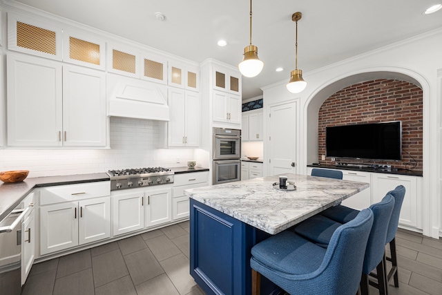5567 Longmont Dr, Houston, TX 77056 - kitchen with appliances with stainless steel finishes, white cabinets, decorative backsplash, a kitchen island, and recessed lighting