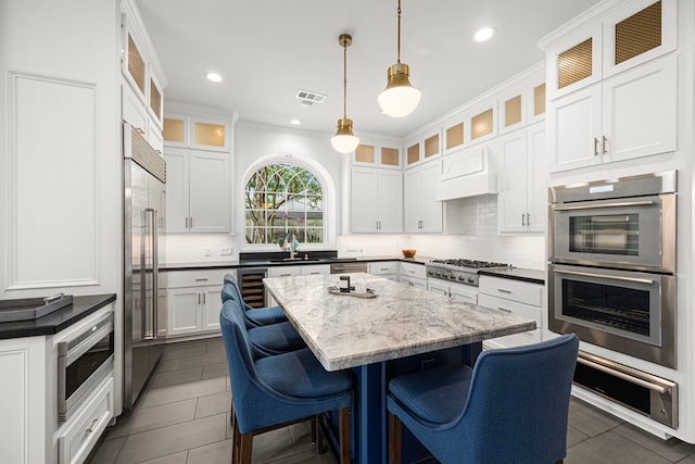 5567 Longmont Dr, Houston, TX 77056 - kitchen with built in appliances, a kitchen island, tasteful backsplash, a kitchen bar, and recessed lighting