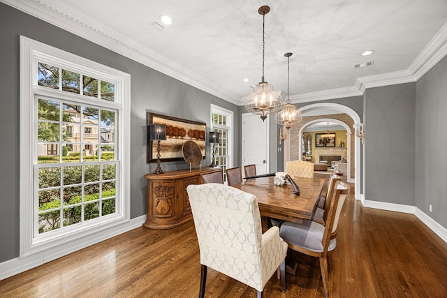 5567 Longmont Dr, Houston, TX 77056 - dining room featuring arched walkways, a chandelier, baseboards, wood finished floors, and crown molding