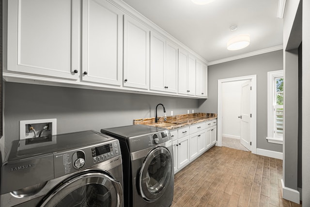 5567 Longmont Dr, Houston, TX 77056 - laundry area featuring separate washer and dryer, crown molding, cabinet space, light wood-style floors, and baseboards