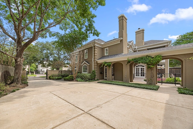 5567 Longmont Dr, Houston, TX 77056 - back of property with a gate, a chimney, stucco siding, roof with shingles, and driveway