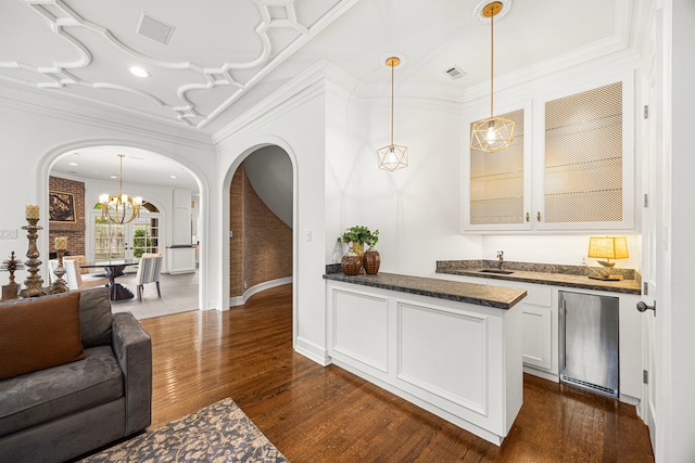5567 Longmont Dr, Houston, TX 77056 - indoor bar featuring arched walkways, crown molding, fridge, dark wood-type flooring, and a chandelier