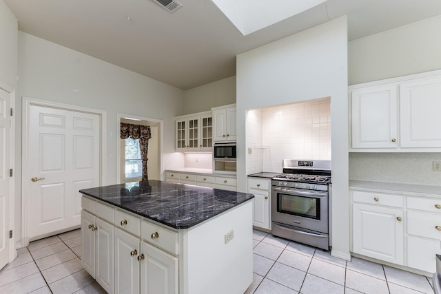 1967 Greentree Dr, Huntsville, TX 77340 - kitchen featuring stainless steel appliances, light tile patterned floors, a skylight, a center island, and white cabinets
