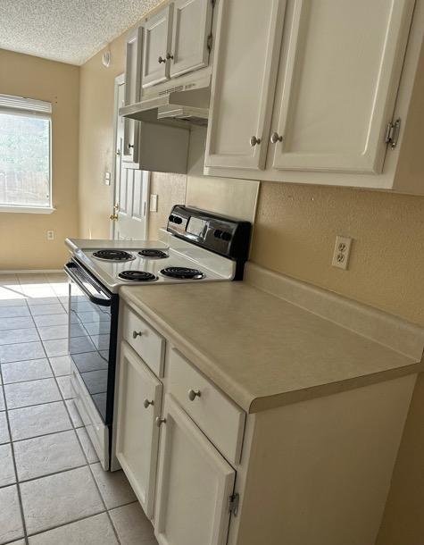 4735 El Vedado St, San Antonio, TX 78233 - kitchen featuring under cabinet range hood, electric range, light countertops, a textured ceiling, and light tile patterned floors