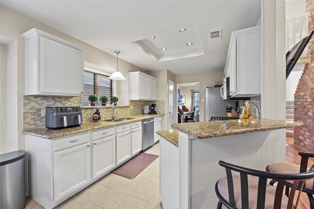 16310 Leamington Ln, Houston, TX 77095 - kitchen featuring stainless steel appliances, a sink, a tray ceiling, backsplash, and a peninsula