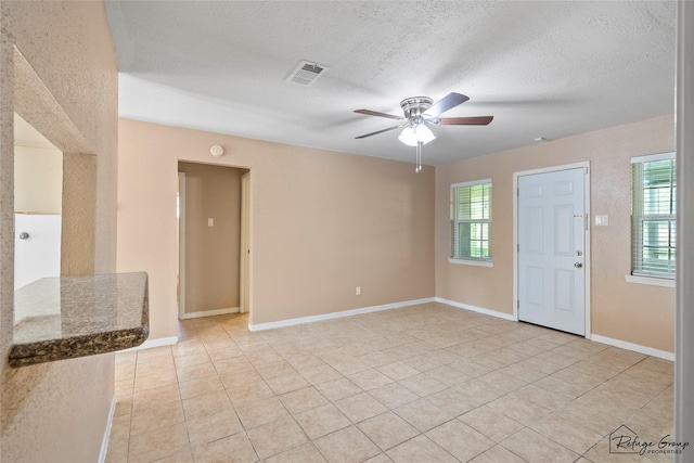 719 Kilpatrick St, Channelview, TX 77530 - unfurnished living room with a ceiling fan, light tile patterned floors, plenty of natural light, and a textured ceiling