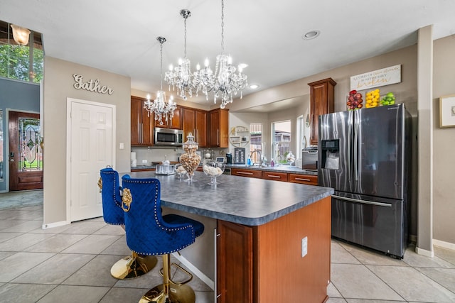 25993 Royal Emerald Ln, Kingwood, TX 77339 - kitchen with appliances with stainless steel finishes, dark countertops, a chandelier, light tile patterned flooring, and a kitchen island