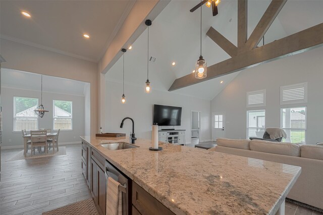 103 Alder Loop, Anahuac, TX 77514 - kitchen featuring stainless steel dishwasher, a sink, open floor plan, light stone counters, and baseboards