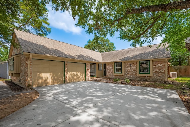 single story home featuring an attached garage, roof with shingles, concrete driveway, central air condition unit, and fence