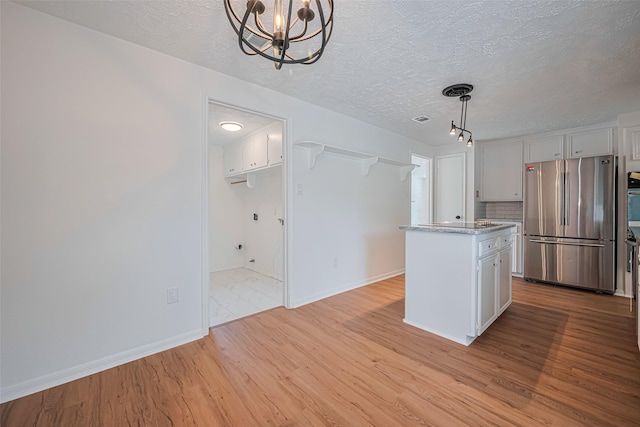 kitchen with freestanding refrigerator, a chandelier, white cabinetry, light wood-style flooring, and a textured ceiling