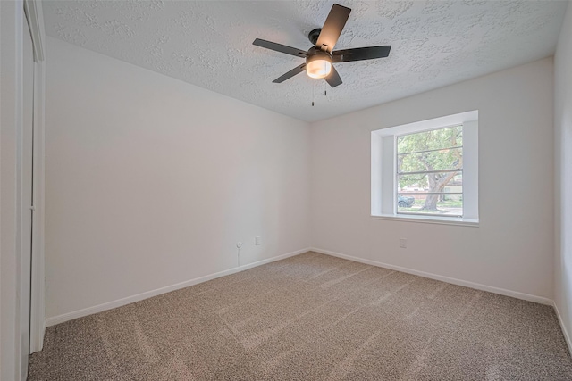 spare room featuring a textured ceiling, light colored carpet, baseboards, and ceiling fan