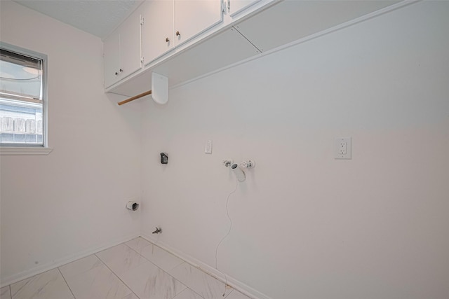 clothes washing area featuring cabinet space, hookup for a gas dryer, light marble finish flooring, and baseboards