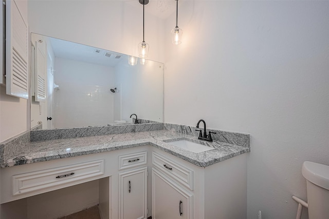 full bath featuring vanity, a shower, and toilet