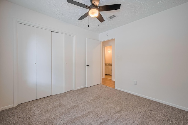 unfurnished bedroom featuring carpet floors, baseboards, a textured ceiling, a closet, and ceiling fan