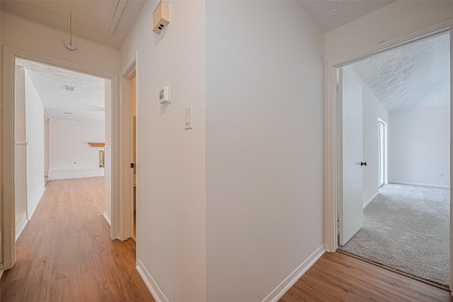 hall with attic access, light wood-style floors, and baseboards