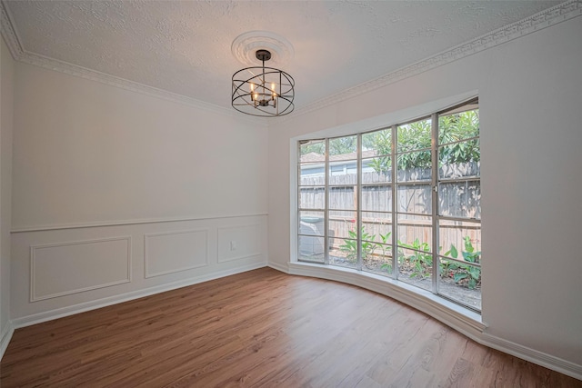 unfurnished room with a chandelier, wood finished floors, ornamental molding, and a textured ceiling