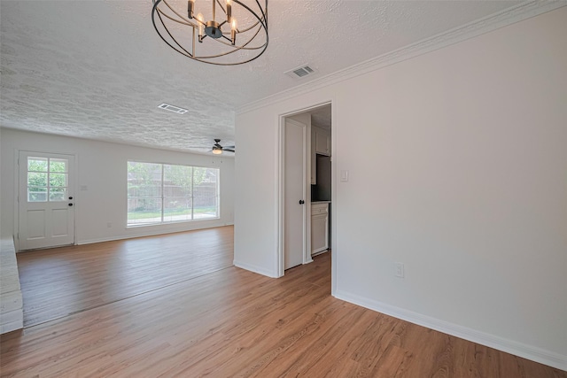 unfurnished living room featuring a textured ceiling, a chandelier, light wood-style floors, baseboards, and ornamental molding