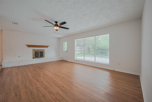 unfurnished living room with wood finished floors, ceiling fan, a textured ceiling, baseboards, and a fireplace