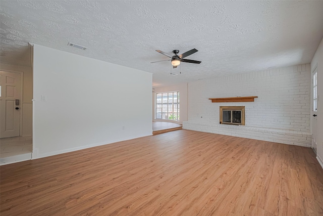 unfurnished living room featuring a textured ceiling, wood finished floors, a ceiling fan, a fireplace, and baseboards