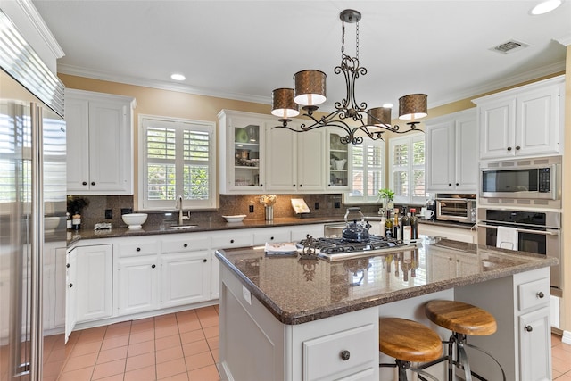 51 Oak Hollow Cir, Lake Jackson, TX 77566 - kitchen featuring built in appliances, a center island, light tile patterned flooring, white cabinets, and ornamental molding