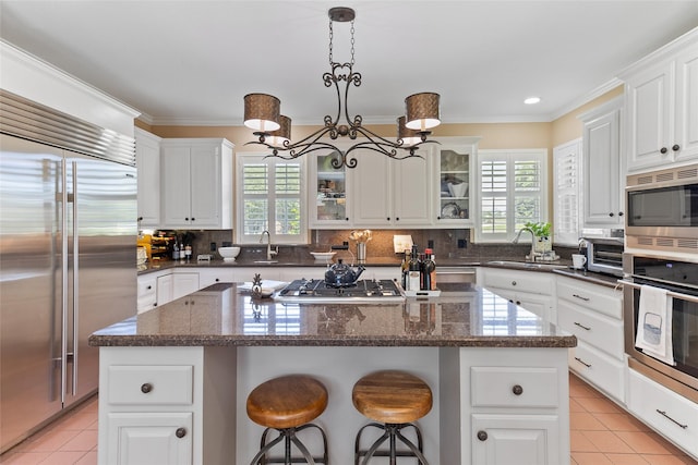 51 Oak Hollow Cir, Lake Jackson, TX 77566 - kitchen featuring built in appliances, healthy amount of natural light, a sink, light tile patterned floors, and crown molding
