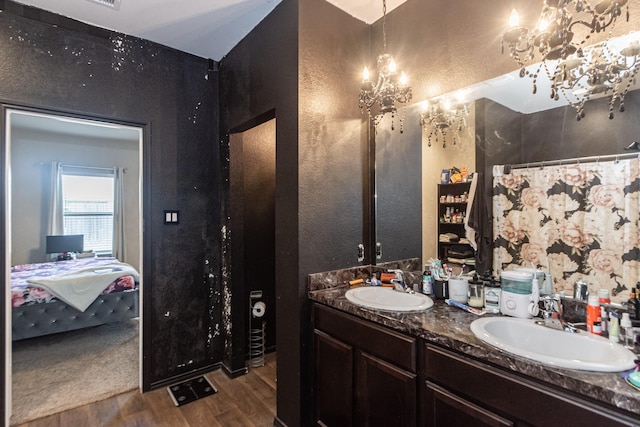 2415 Georgina Falls Dr, Spring, TX 77373 - bathroom featuring wood finished floors, a chandelier, a textured wall, ensuite bathroom, and double vanity