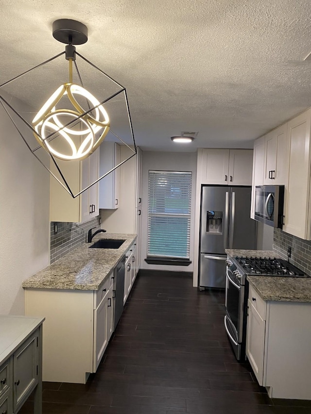 5108 Longshadow Dr, Dickinson, TX 77539 - kitchen featuring stainless steel appliances, a sink, dark wood-style floors, white cabinetry, and a textured ceiling