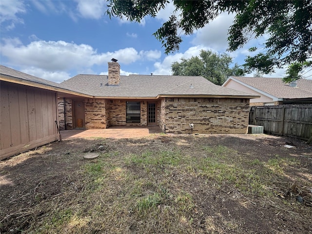 405 Tudor Ct, Deer Park, TX 77536 - rear view of property featuring brick siding, a patio area, a chimney, a shingled roof, and central AC
