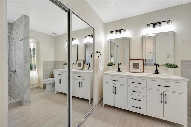 11710 Brettwood Cir, Houston, TX 77089 - bathroom with toilet, a marble finish shower, double vanity, tile walls, and wood finished floors