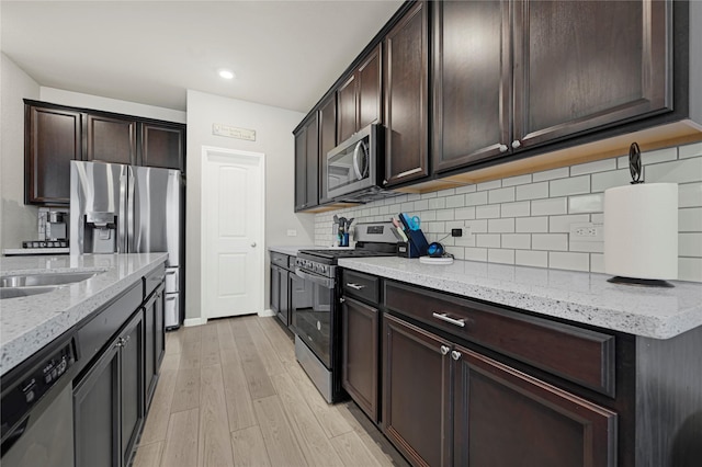 21626 Sage Landing Ln, Katy, TX 77449 - kitchen featuring stainless steel appliances, light wood-style floors, light stone counters, tasteful backsplash, and dark brown cabinetry