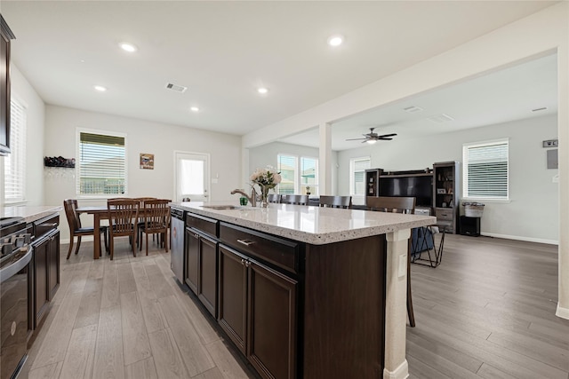 21626 Sage Landing Ln, Katy, TX 77449 - kitchen with a kitchen bar, a sink, dark brown cabinetry, light wood-style flooring, and appliances with stainless steel finishes