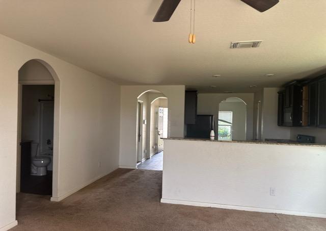 15215 Snug Harbor Way, Von Ormy, TX 78073 - kitchen featuring black fridge, carpet flooring, arched walkways, a ceiling fan, and baseboards