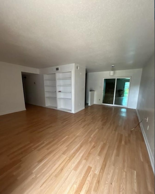 5625 Antoine Dr Unit 705, Houston, TX 77091 - unfurnished living room featuring a textured ceiling, light wood-style flooring, and built in shelves