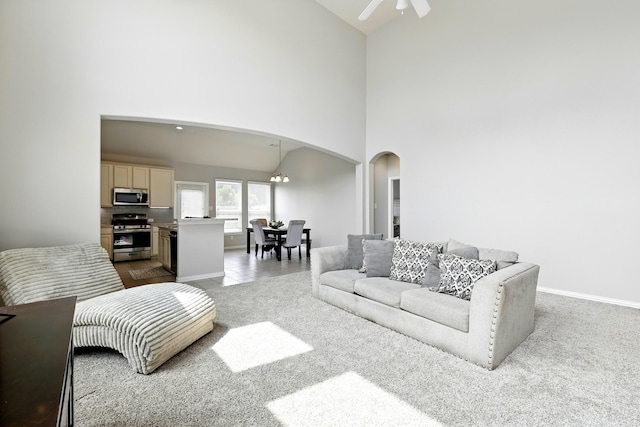 32719 Oak Heights Ln, Brookshire, TX 77423 - carpeted living area with arched walkways, a ceiling fan, a high ceiling, and baseboards